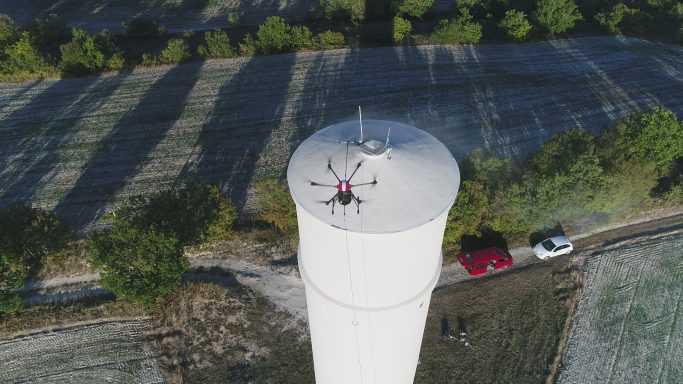 Vue aérienne d'un réservoir d'eau avec un drone en haut et une voiture à proximité.